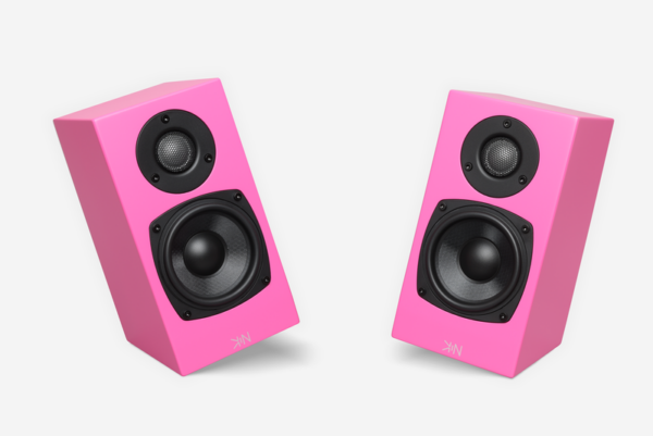 Two pink rectangular Totem - Kin One bookshelf speakers with visible black drivers are positioned at an angle facing each other. The Kin One speakers feature a tweeter and a woofer, and have a small logo near the bottom.