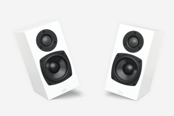 A pair of Totem Kin One bookshelf speakers, compact and white with circular black drivers, stands angled facing each other against a pristine white background.